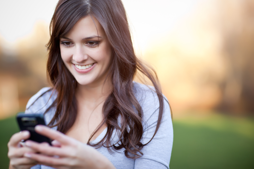 woman smiling while looking at her cell phone