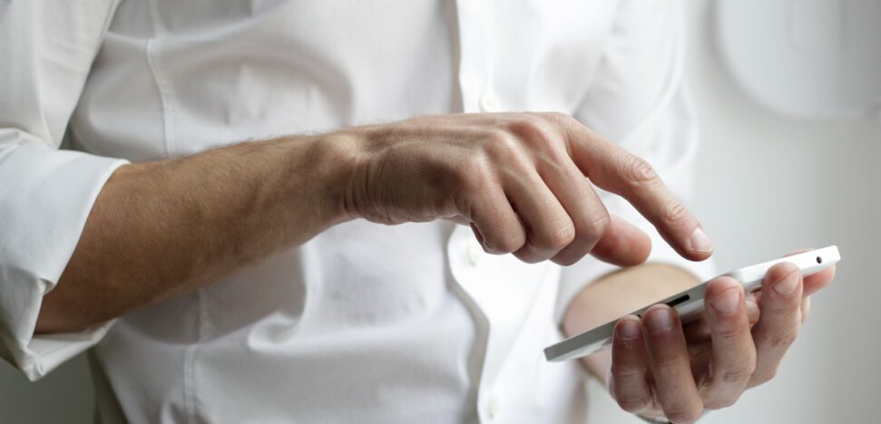 man typing on cell phone in his hand