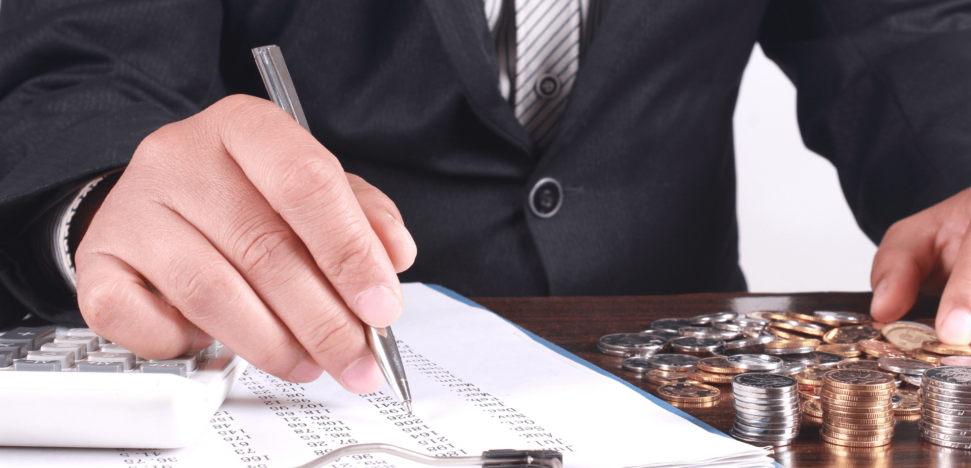 man with clipboard and coins on desktop