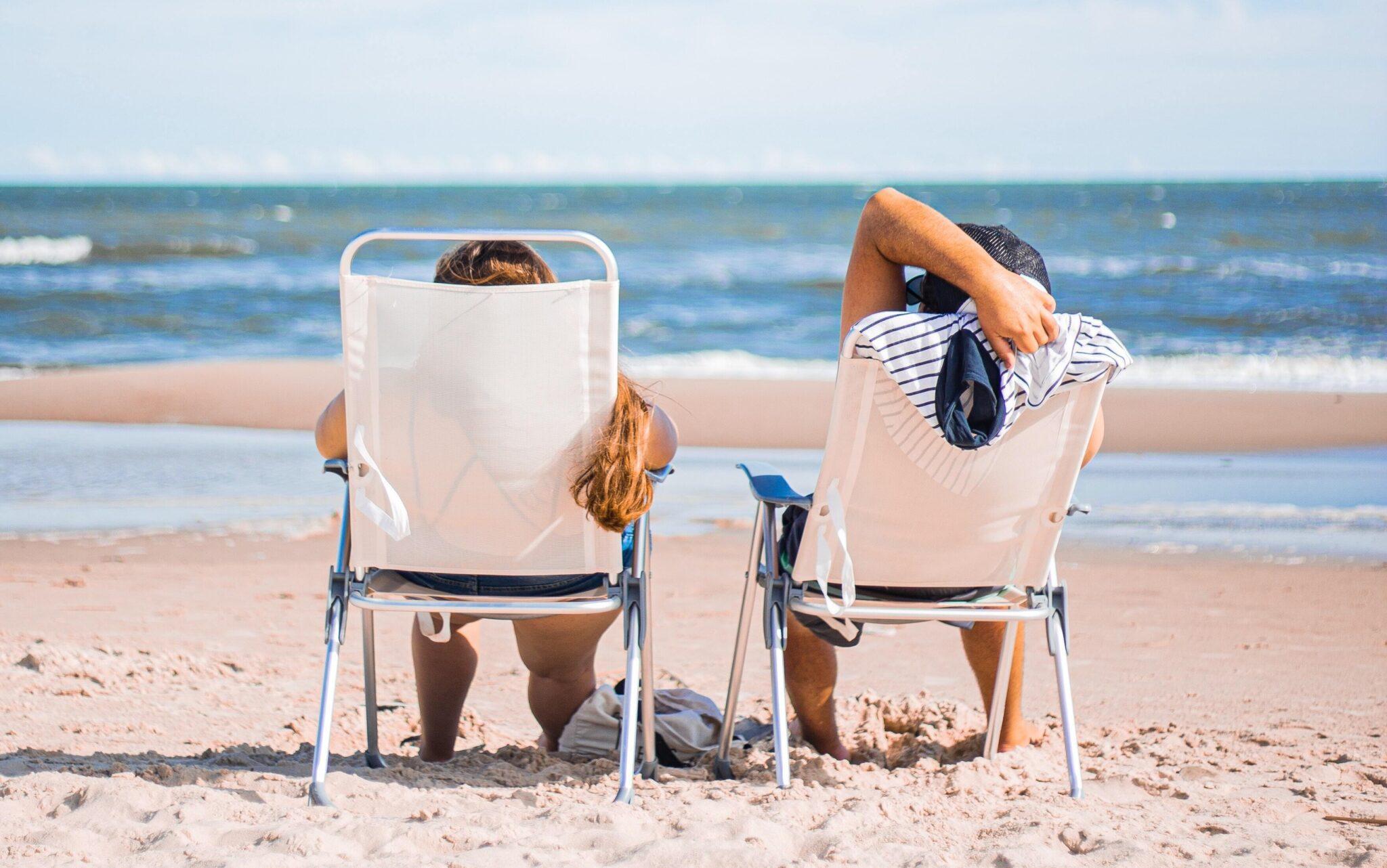 man and woman sitting on beach in chairs