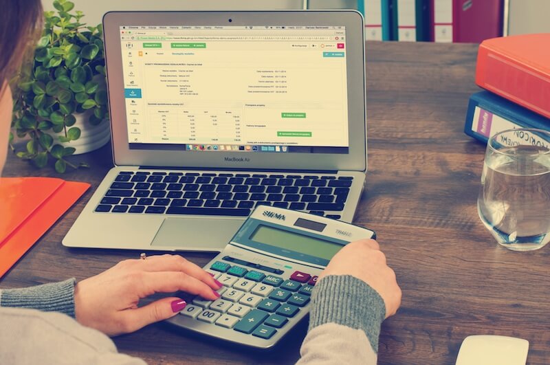 woman doing work on laptop and calculator